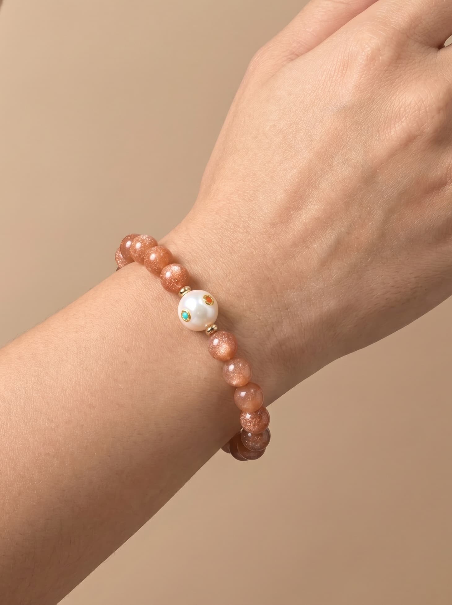 Sunstone and pearl bracelet worn on wrist